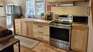 Une cuisine moderne dotée d’un réfrigérateur en acier inoxydable, d’un évier à deux bacs, d’un four encastré, d’un four à micro-ondes et de meubles de rangement en bois.
