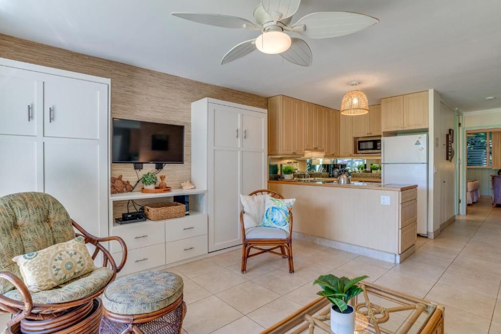 A modern kitchen with a central island, white cabinetry, and a ceiling fan.