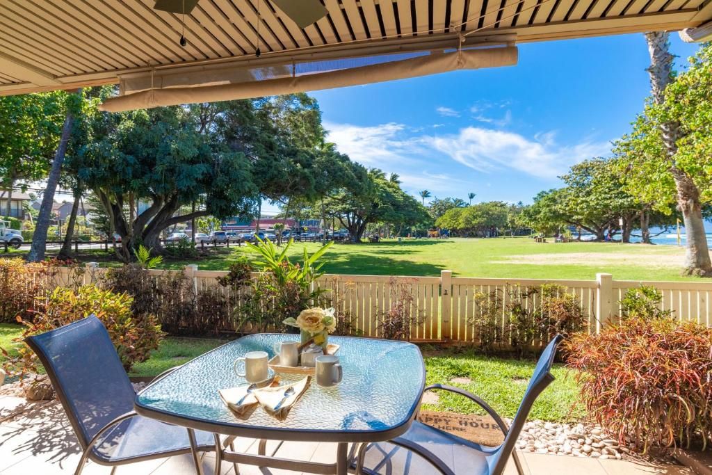 An outdoor patio with a table and chairs, surrounded by greenery and a view of a park.