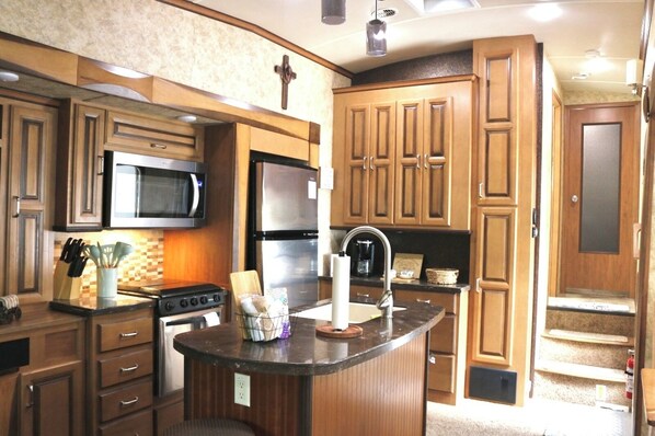 A kitchen with wooden cabinets, a microwave, a stove, and a sink.