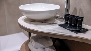 A bathroom with a large white basin, a set of toiletries, and neatly rolled towels. - Soul of Trento San Martino (Trento)