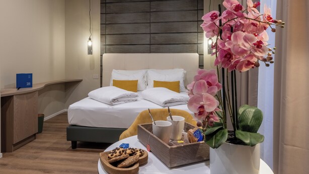 A hotel room with a bed, bedside table, and a potted orchid. - Soul of Trento San Martino (Trento)