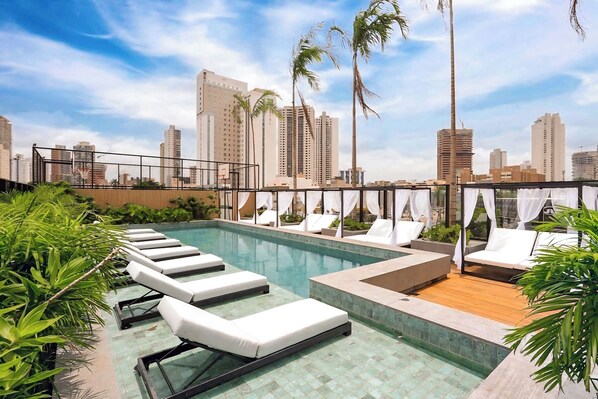 Una piscina techada, una piscina al aire libre, sombrillas