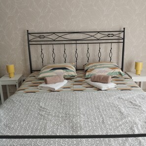 Un lit avec une couvre-lit à motifs, deux oreillers et une tête de lit en métal.