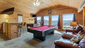 Una habitación acogedora con mesa de billar, mesa de fútbolín, sofá y zona de bar.