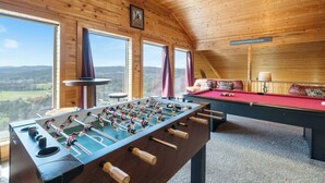 Una habitación acogedora con mesa de fútbol de mesa, mesa de billar y ventanas amplias que ofrecen una vista panorámica.