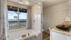A bathroom with a bathtub, a window with a view, and a sink with a bowl.