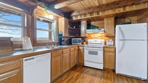 Una cocina con armarios de madera, lavavajillas, estufa, microondas y refrigerador.