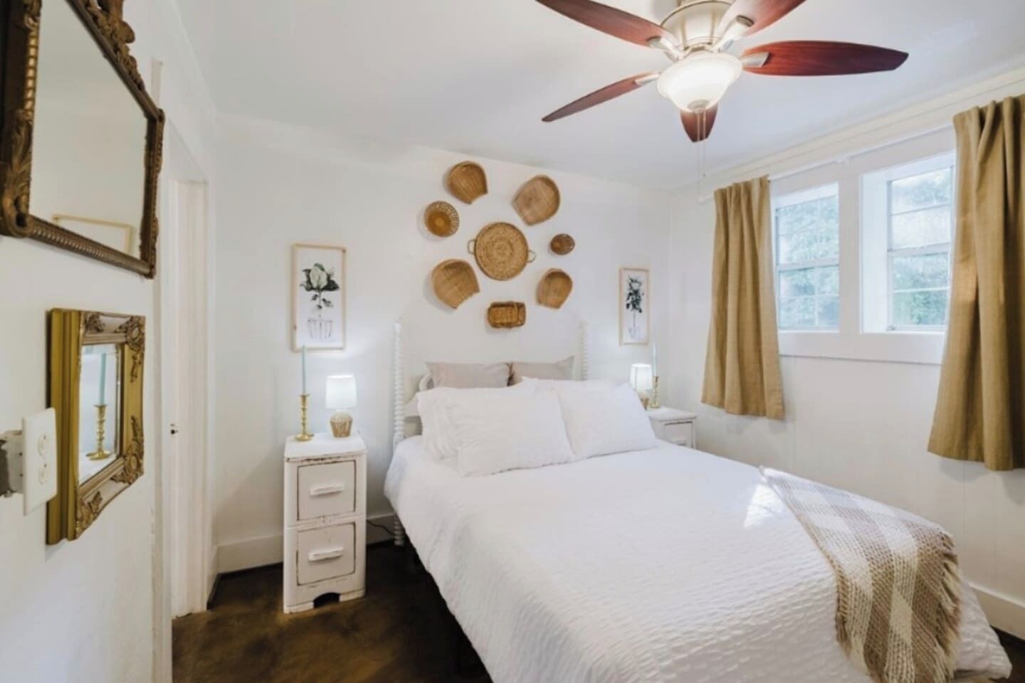 A bedroom with a bed, a ceiling fan, a window with curtains, and wall decorations.