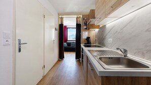 Een moderne keuken met een grote gootsteen, houten kastjes en uitzicht op een woonruimte.