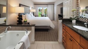 Ein Hotelzimmer mit einem großen Bett, einem Badezimmer mit einer Badewanne und Blick ins Freie.