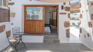 Una stanza con una porta di legno, un tavolino con una sedia e un cartello con la scritta 'TABAYESCO'.