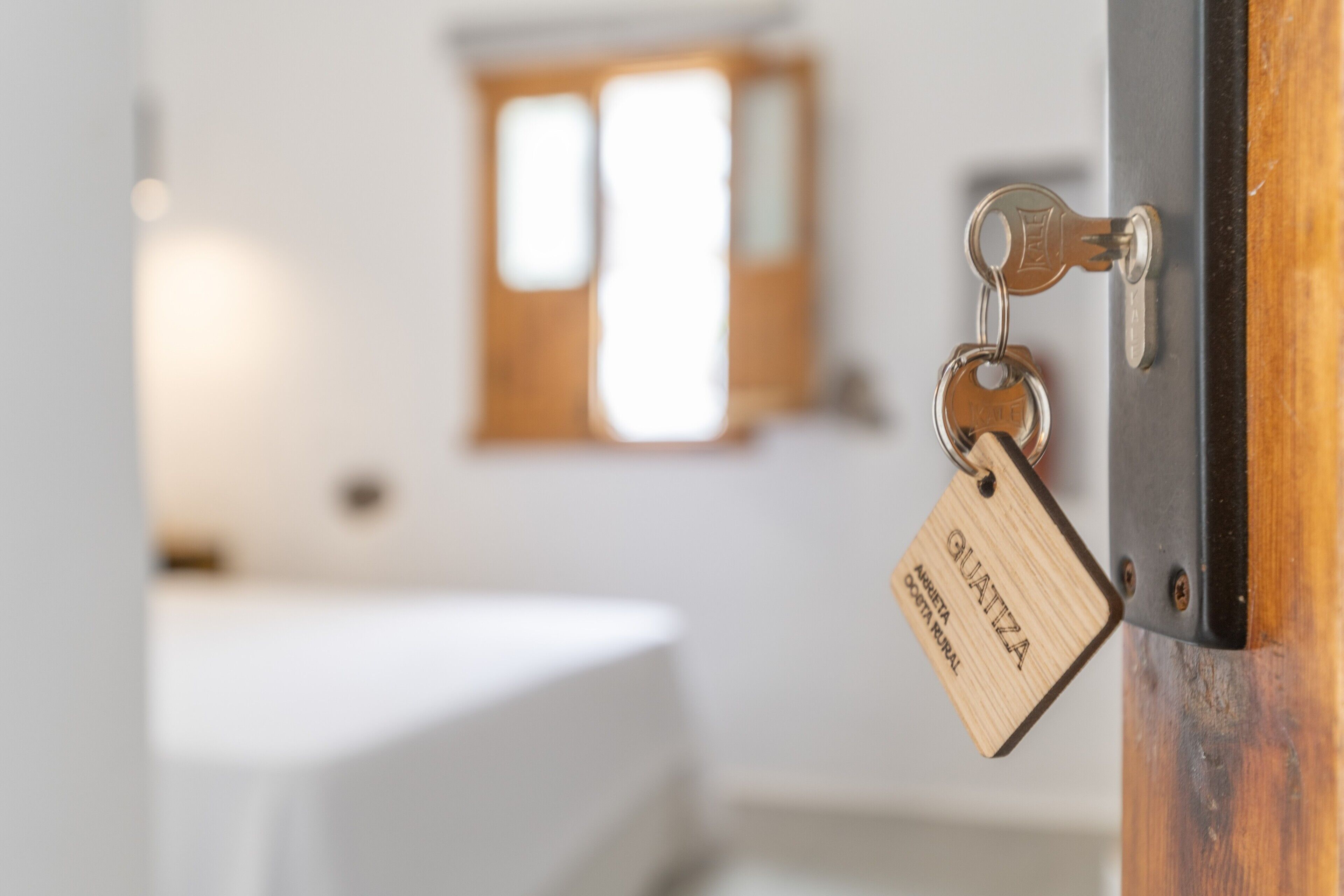 Une porte en bois avec un porte-clés portant l’inscription « QUATZA » et une clé en métal.