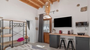 Een compacte kamer met een stapelbed, een bureau met krukken, een televisie en een kitchenette.