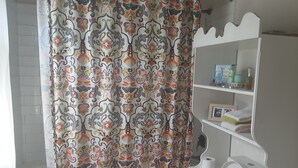 A bathroom with a shower curtain featuring a floral pattern, a toilet, and a shelf with toiletries. -  A Hidden Bed & breakfast with live-in host  Private, Peaceful with Plunge pool. (Christ Church)