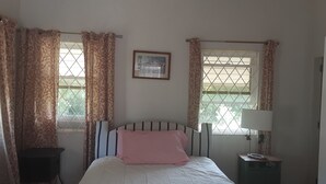 A bedroom with a bed, a nightstand, a lamp, and a window with curtains. -  A Hidden Bed & breakfast with live-in host  Private, Peaceful with Plunge pool. (Christ Church)