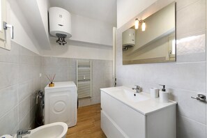 Ein modernes Badezimmer mit Waschmaschine, Waschbecken und Spiegel.