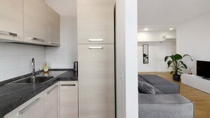 Eine moderne Küche mit schwarzem Arbeitsplatz, Edelstahl-Spüle und hellen Schränken.