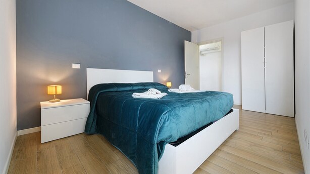 Ein Schlafzimmer mit Bett, Nachttischen, einer Lampe und einem Kleiderschrank.