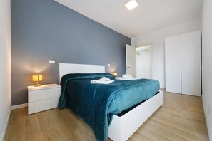 A bedroom with a bed, nightstands, a lamp, and a wardrobe.