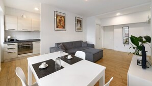 Ein zeitgemäßer Wohnraum mit Küche, Essbereich und einem grauen Sofa.