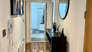 Un couloir avec un téléphone, un miroir et une porte en bois.