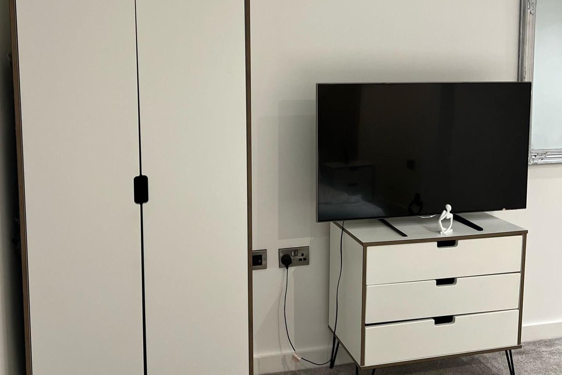 Ein Fernseher auf einem weißen Schrank mit einer Steckdose und einem Kabel.