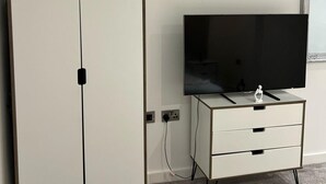 Un téléviseur posé sur un meuble blanc, avec une prise de courant et un câble.