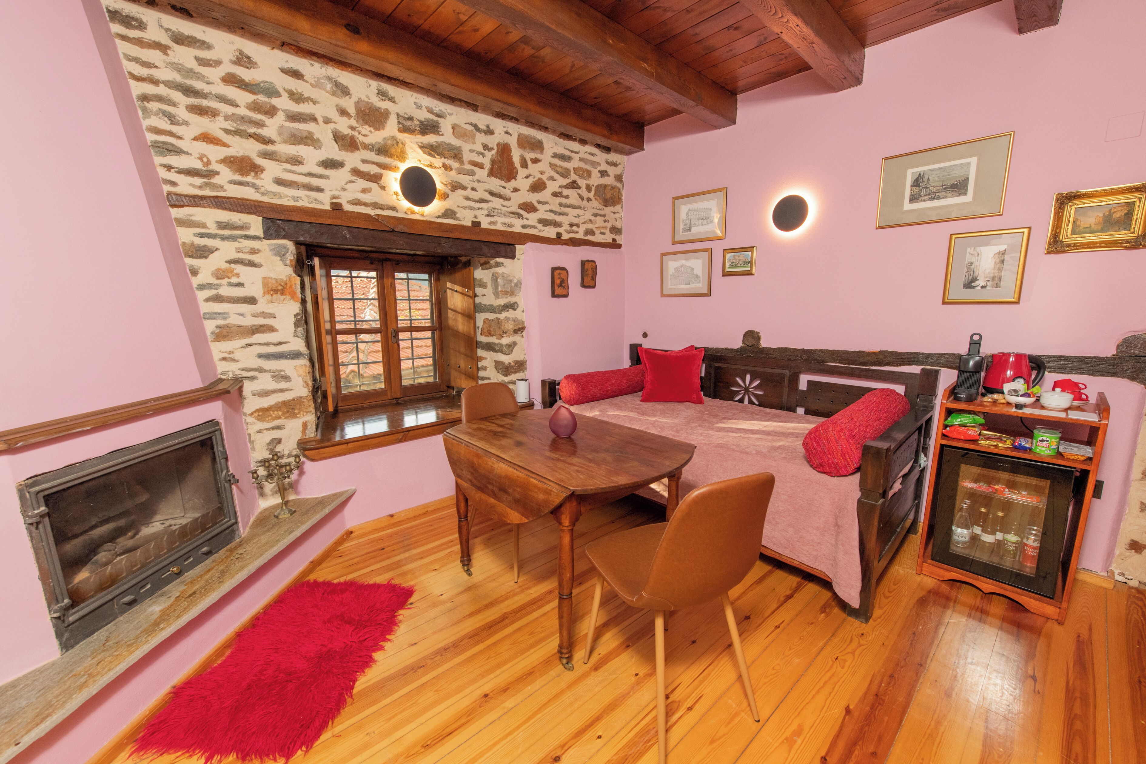 Une pièce chaleureuse avec un mur en pierre, des meubles en bois, une cheminée et un petit réfrigérateur.