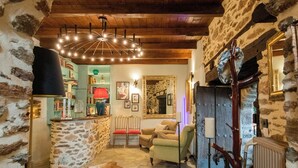 A rustic interior with stone walls, a wooden ceiling, a stone floor, a leather rug, a wooden chair, a radiator, and a mirror. - Archontiko 1716 (Volos)