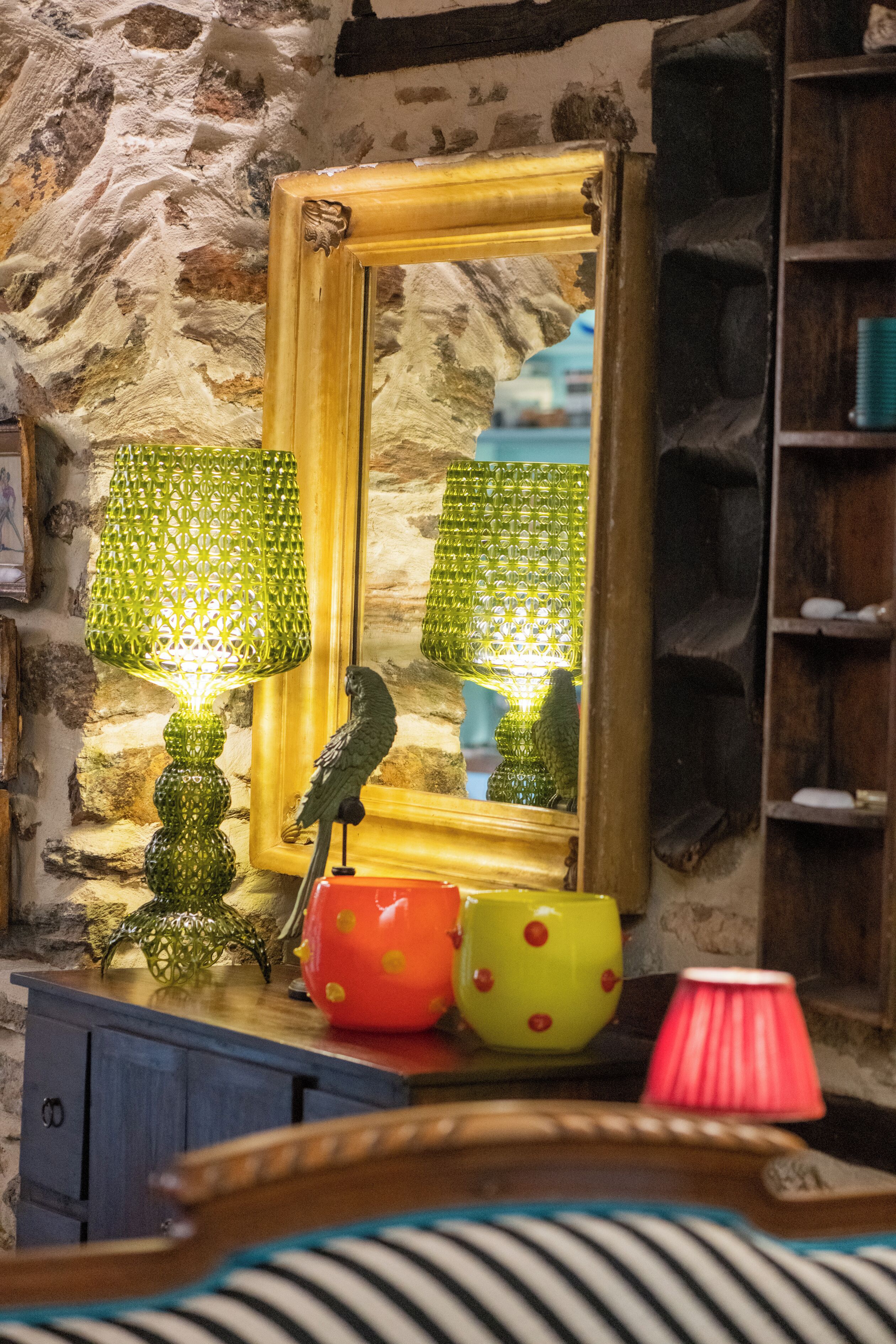 A room with a stone wall, a wooden cabinet, a mirror, and a lamp.