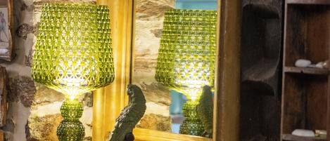 A room with a stone wall, a wooden cabinet, a mirror, and a lamp.