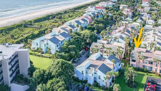 Zona residencial costera con edificios modernos, una playa y un aparcamiento.