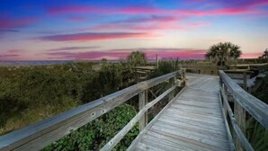 Una pasarela de madera que conduce a un mirador con vistas al horizonte y al atardecer.