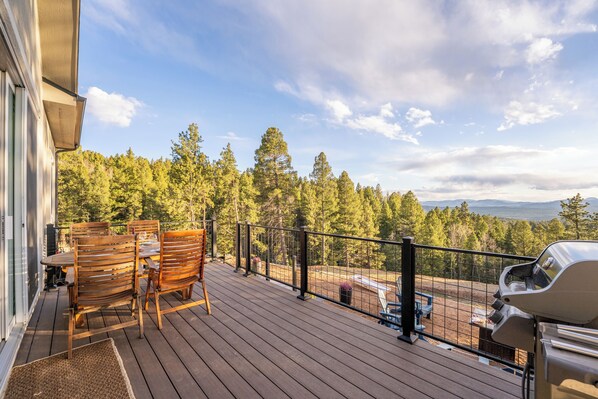 A wooden deck with outdoor furniture, a grill, and a view of a forested area. - ViewHouse - Hot Tub - Trails (Florissant)