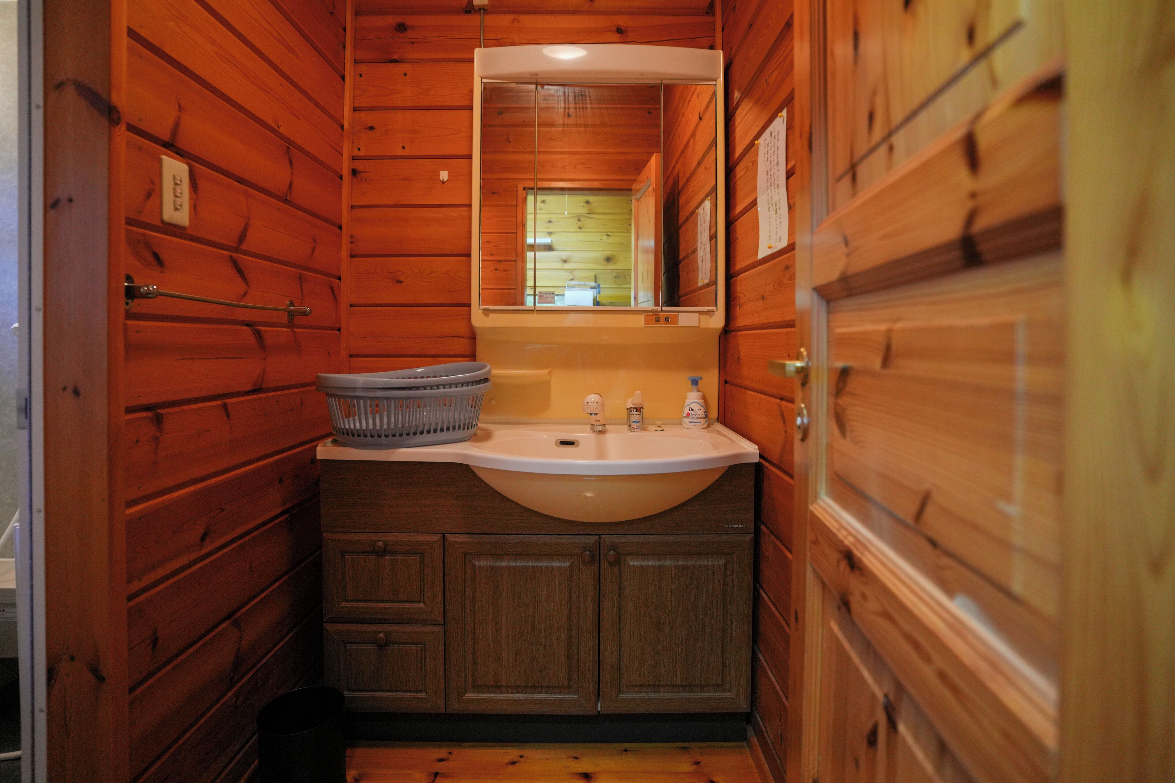 Bagno di una baita in legno con lavandino, specchio e mobili.