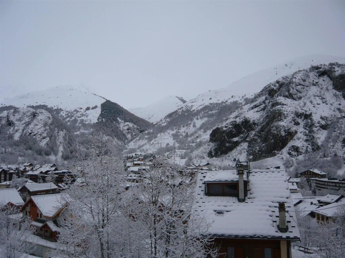 Ein verschneites Dorf mit traditionellen Holzhäusern und einem Berg im Hintergrund.