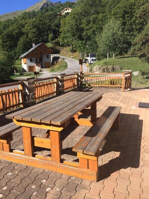 Ein Picknickbereich mit Holzbänken und -tischen, umgeben von einem Backsteinweg.