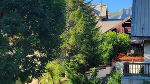 A residential area with a house featuring a sloped roof, a large tree, and a mountain in the background. - 300m from ski slopes, 2nd floor, swimming pool, balcony, tv, 45m², Valloire (Valloire)