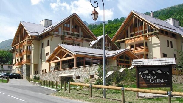 A chalet-style building with a stone facade and wooden balconies, labeled "Les Chalets du Galibier." - 300m from ski slopes, 2nd floor, swimming pool, balcony, tv, 45m², Valloire (Valloire)