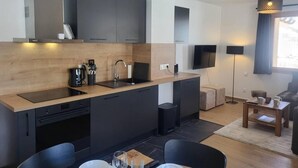 A modern kitchen with dark cabinetry, a wooden countertop, and a dining area with a table and chairs. - 15m from ski slopes, 2nd floor, view ski slopes, balcony, tv, ski locker, 55m², Valmorel (Valmorel)