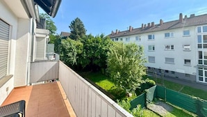 A balcony with a view of a green garden and neighboring buildings. - Family Apartments Near City Centre (Frankfurt)