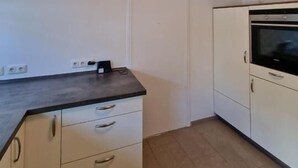 A kitchen with white cabinets, a black countertop, and a built-in oven. - Family Apartments Near City Centre (Frankfurt)