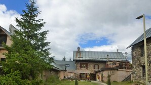 A stone building with a metal roof, a wooden deck, and a gravel path leading to the entrance. - 1st floor, terrace, tv, ski locker, 85m², Valloire (Valloire)