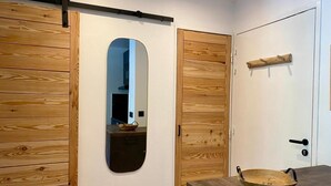 A room with wooden sliding doors, a mirror, a wooden shelf, and a bowl on a counter.