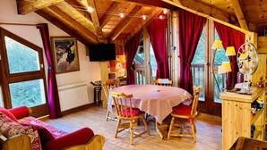 Ein gemütliches Blockhauss-Interieur mit einem Holzesstisch, roten Vorhängen und einem an der Wand befestigten Fernseher.