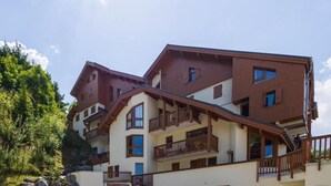 Ein mehrstöckiges Hotel mit Balkonen, einer Garage und einer Steinmauer.