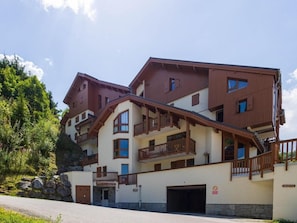 Ein mehrstöckiges Hotel mit Balkonen, einer Garage und einer Steinmauer.