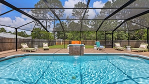 A covered outdoor swimming pool with lounge chairs and a stone feature in the center. - Spacious, Family-Friendly 5 Bedroom Home with Salt Water Pool (Navarre)
