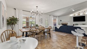 A modern living room with a dining area, a fireplace, and a TV mounted on the wall. - Spacious, Family-Friendly 5 Bedroom Home with Salt Water Pool (Navarre)